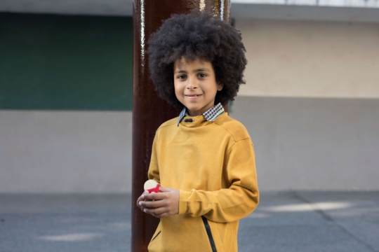 Petit garçon en train de sourire avec un babybel à la main